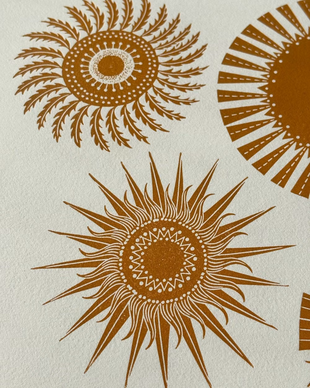hand carved woodcut sun print photograph - I’ve carved a bit more from the first comet blocks so now they look like mini suns. Bright sunlight this morning on my desk too, and I’ve been watching the blue tits checking out the bird box. Last year I had a nest but sadly the box fell off the wall, so I’ve made sure it’s securely attached this year.  #comets #spring #printmaking #linoprint #popmembers