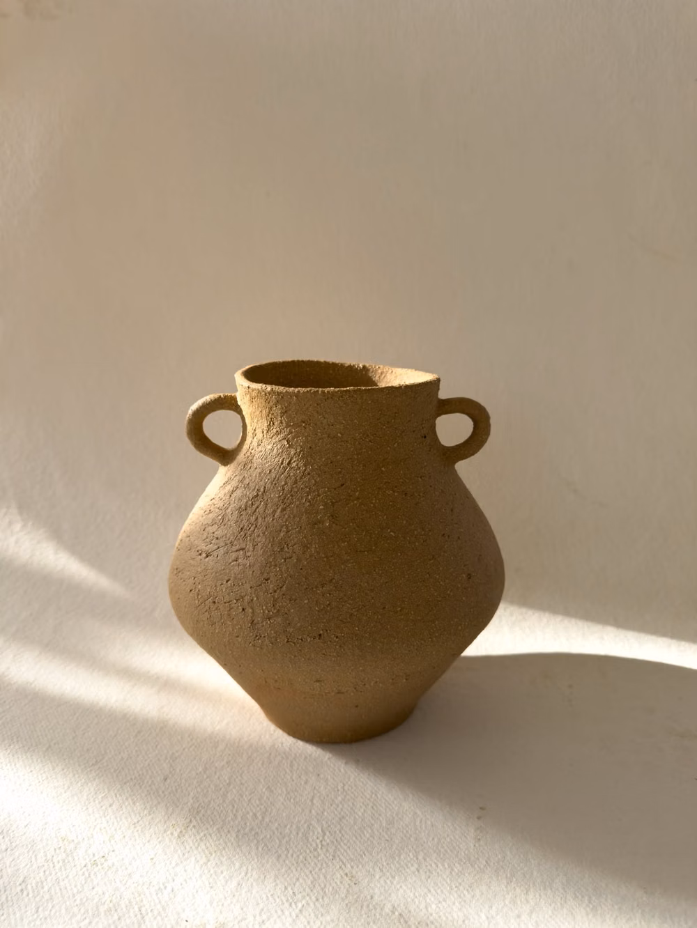 single unglazed ceramic vessel white background photograph - Introducing Dione, inspired by the ancient goddess. This vessel holds a distinct form and irregular mouth, giving it a unique, irreplaceable character. 

Hand- coiled from stoneware clay with coarse grog that creates a rough and organic texture on the surface. Left unglazed on the outside to show the natural beauty of the clay, and glazed on the inside for functional use.

#pottery #ceramics #ceramicart #ceramicvessel #ceramicvessels #potteryvases
