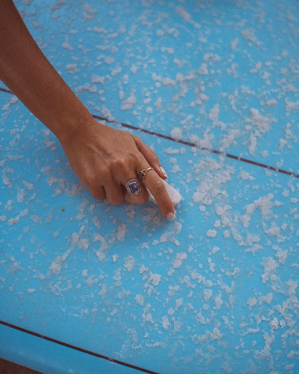 surfer rubbing wax bar on surfboard deck close up photograph - Wax on, worries off.  Board-ready, island life fully loaded. 🏄‍♀️